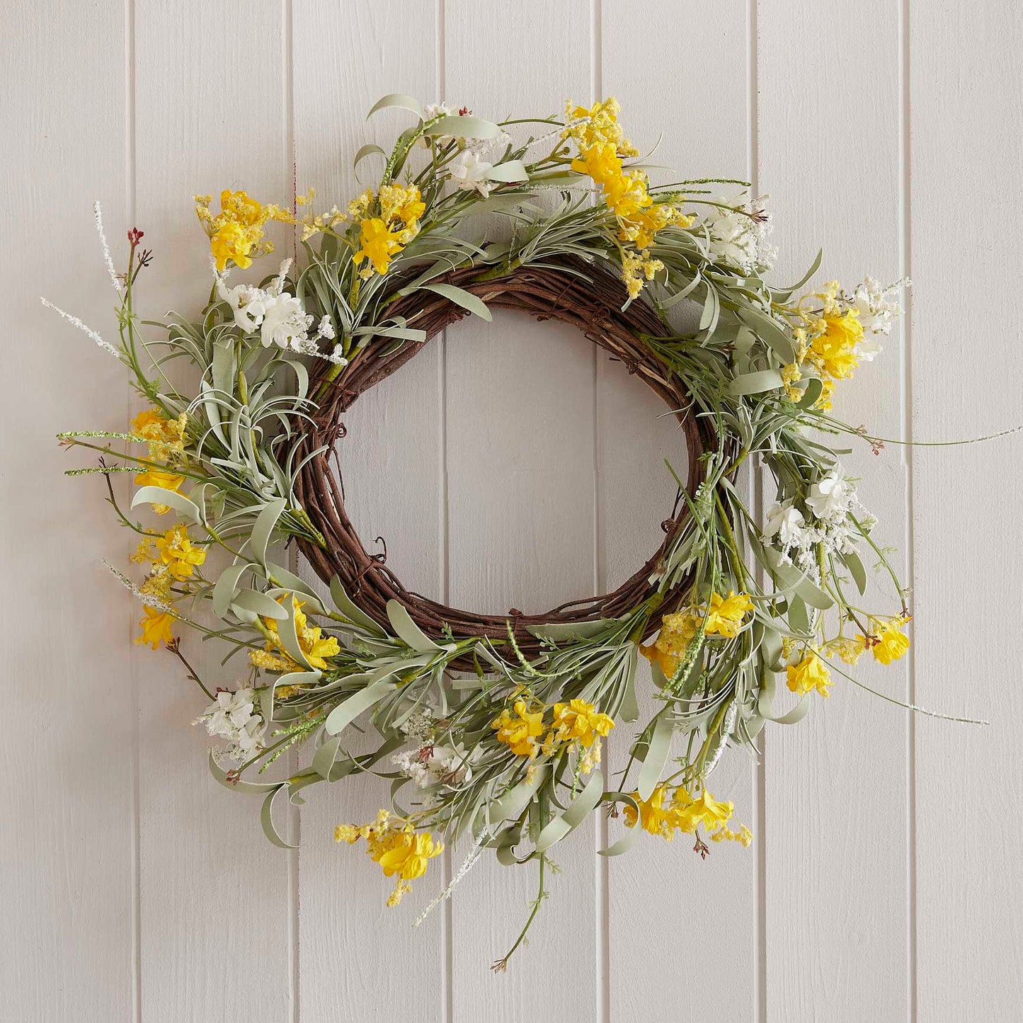 yellow artificial flower spring wreath hanging on a front door